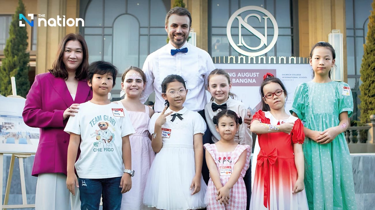 Adults and children posing in front of the Dulwich College International School Bangkok entrance at an opening event.